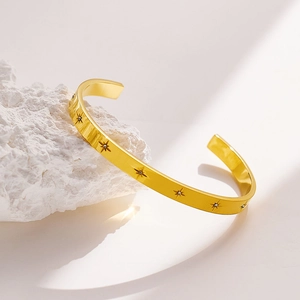 Elegant gold-plated starburst cuff bracelet with zircon inlays on white rock