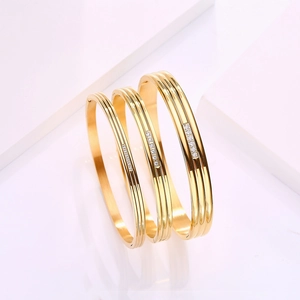 Detailed close-up of three layered gold stainless steel bangles with sparkling zircon stones