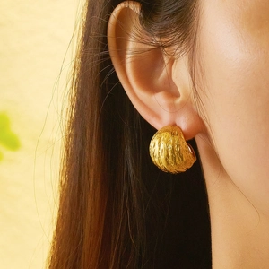 Gros plan d'une boucle d'oreille dorée texturée vintage avec finition martelée