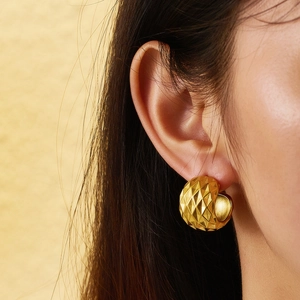 Détail d'une boucle d'oreille en titane doré avec surface texturée à coupe diamant