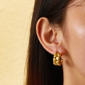 Gros plan de boucles d'oreilles cœur dorées portées à l'oreille avec texture métal