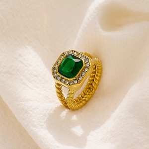 Detalle de un anillo de oro vintage con circonita esmeralda grande y banda trenzada