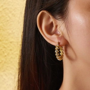 Detail view of gold earrings with leaf texture and sparkling inlaid zircons