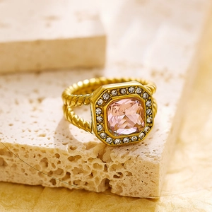 Vista macro de anillo vintage dorado con circón rosa cuadrado y banda de cuerda torcida