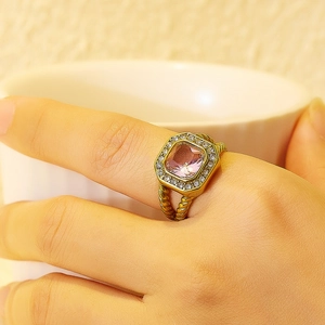 Detalle de anillo vintage dorado con circón rosa cuadrado y banda de estilo trenzado