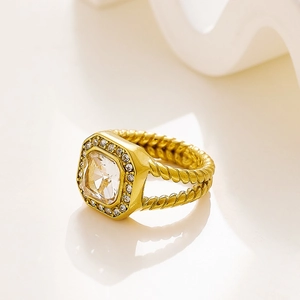 Detalle de anillo dorado vintage con circonita cuadrada y banda de cuerda trenzada