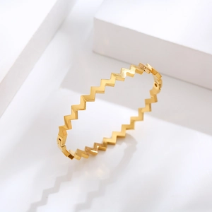 Moderno brazalete de acero de titanio dorado con un diseño geométrico de zigzag