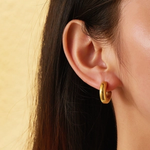 Close-up of a 18k gold plated chunky hoop earring with zircon inlay worn by a female model