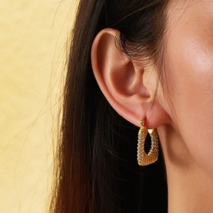 Detail of 18k gold plated rectangular hoop earring with zircon inlay and textured finish