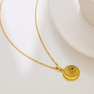Λεπτομέρεια από επιχρυσωμένο μενταγιόν 18k με σχέδιο ήλιου και κεντρική πράσινη πέτρα