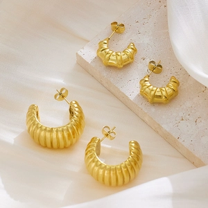 Vue détaillée de boucles d'oreilles créoles dorées en C avec texture nervurée