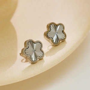 Macro detail of silver floral stud earrings with sunburst texture and center diamond