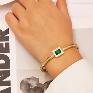 Detail of 18k gold plated bangle featuring a rectangular green zircon and pavé crystals