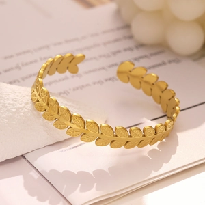 Détail du bracelet manchette doré mat avec motif de feuilles de laurier et anneau ajustable