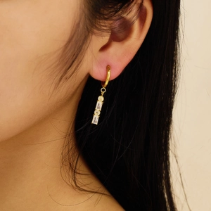 Close-up of elegant gold drop earrings featuring geometric clear cubic zirconia stones