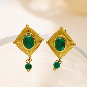 Detailopname van vintage gouden oorbellen met groene malachiet en zonnestraalstructuur