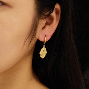 Detail of 18k gold plated Hamsa hand earrings with blue stone and pavé crystal accents