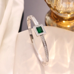 Close-up of silver steel bracelet featuring rectangular emerald stone and pave set zircons