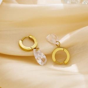 Elegant gold hoop earrings featuring large pear-shaped faceted crystal drops on satin background