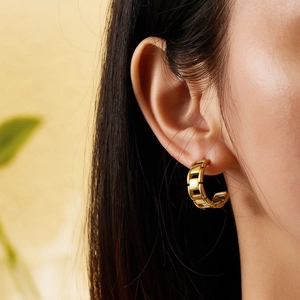 Vue rapprochée d'une boucle d'oreille dorée avec texture de chaîne et motif tressé