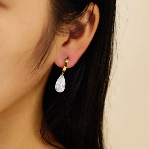 Macro detail of drop-shaped faceted crystal earrings in polished gold settings