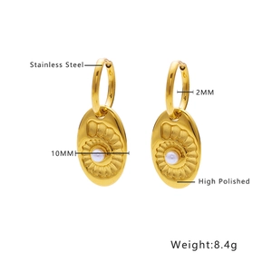 Detail of high polished gold stainless steel earrings with shell and white pearl charms