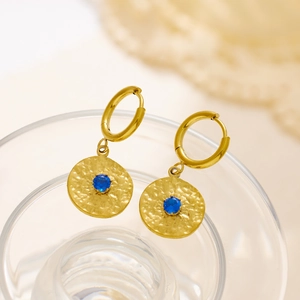 Detail of vintage gold hoop earrings with hammered metal discs and blue gemstones