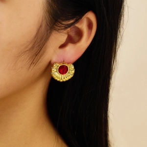 Detail van vintage gouden oorbellen met een rode edelsteen en sprankelende strass-steentjes