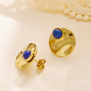 Detail van vintage gouden klaver oorbellen met gehamerde textuur en blauwe stenen