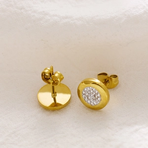 Detailopname van gouden vintage oorknopjes met fonkelende zirkoon inleg en vlindersluiting