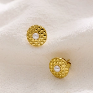 Macro detail van vintage gouden oorknopjes met ruitpatroon en centrale parel