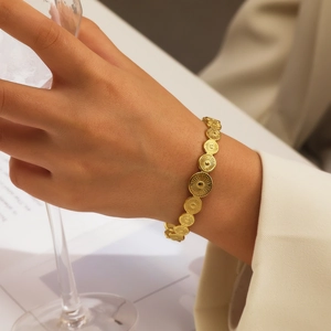 Détail d'un bracelet gourmette doré avec maillons à relief soleil porté par un mannequin