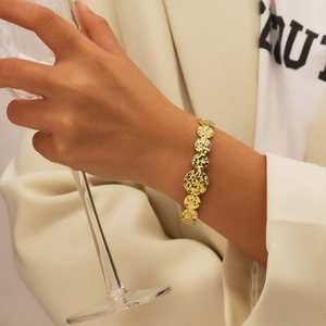 Vue détaillée d'un bracelet doré à disques martelés porté avec une tenue élégante chic