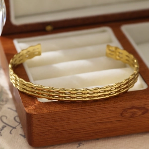 Détail macro du bracelet jonc doré 18 carats à texture ondulée dans son coffret en bois