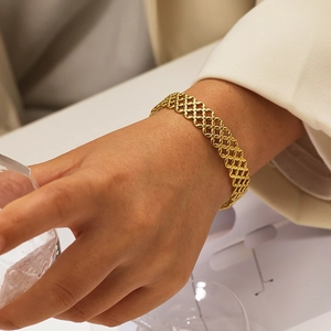 Gros plan d'un bracelet manchette en C doré avec texture en maille creuse et motif élégant
