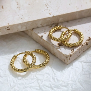 Detail of gold hoop earrings showing fine snake texture and secure hinge closure mechanism