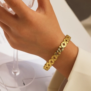 Détail du bracelet manchette tressé doré avec texture brossée sur le poignet