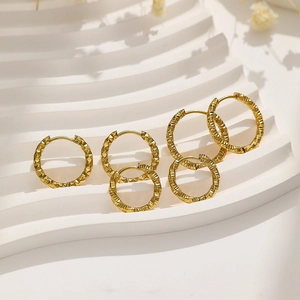 Macro detail of five-piece gold titanium steel hoop earrings with textured geometric facets