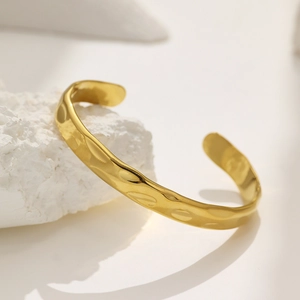 Bracelet manchette C doré minimaliste avec texture martelée sur une pierre blanche
