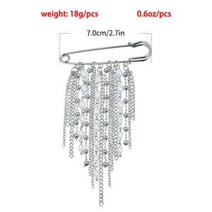 Détail d'une broche à franges argentées avec perles et longues chaînes sur fond blanc