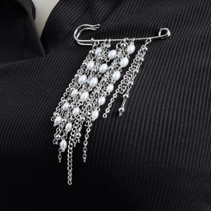 Broche argentée tendance avec de longs glands et perles blanches sur tissu rayé