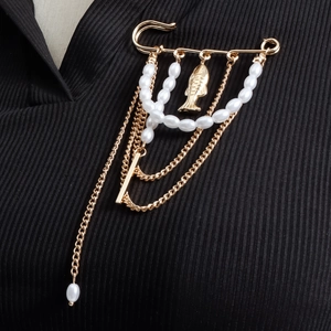 Broche dorée vintage avec chaînes de perles et pendentif poisson sur tissu noir