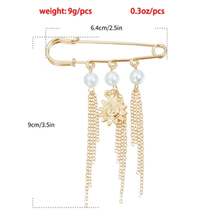 Detail view of gold safety pin brooch with smiley sun charm and long tassel chains