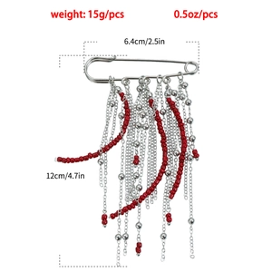 Détail de la broche épingle à nourrice avec perles rouges et pompons multi-chaînes