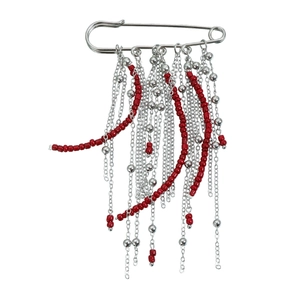 Broche épingle à nourrice vintage avec glands argentés et perles rouges sur fond blanc