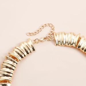 Gros plan sur un collier à maillons dorés avec fermoir mousqueton et détails texturés