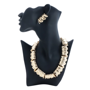 Ensemble collier et boucles d'oreilles en métal doré plissé sur un buste de femme noir