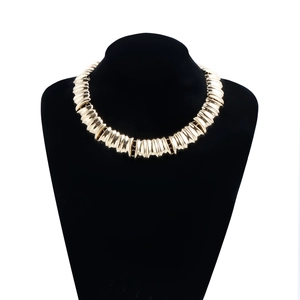 Détail du collier ras du cou doré avec texture plissée verticale et finition polie chic