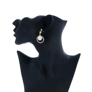 Dettaglio di orecchini vintage con perle e strass su una silhouette nera elegante