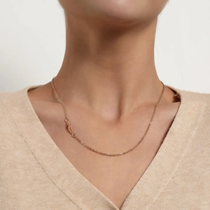 Élégant collier doré avec pendentif croix porté avec un pull beige pour un look minimaliste